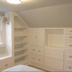 an attic bedroom with built - in shelving and windows