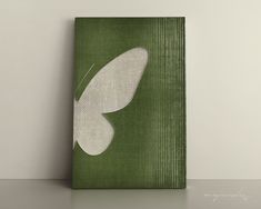 a green canvas with a white butterfly painted on it's side, sitting on a table