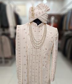 a white dress with pearls on the neck and headpiece is displayed in a store