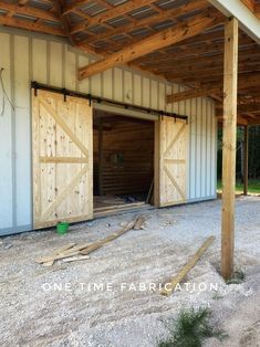 the inside of a building with two open doors and wood planks on the floor