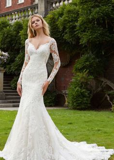 a woman in a white wedding dress standing on the grass