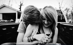 two young women hugging each other in the back of a pick up truck with houses in the background