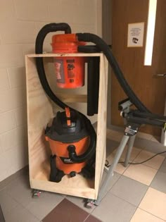 an orange and black vacuum sitting inside of a wooden box