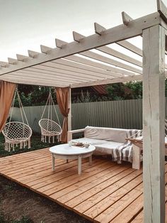 an outdoor living area with wooden decking and white furniture on top of the wood planks