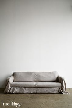 a couch sitting in front of a white wall with the words true things written on it