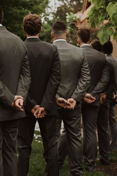 a group of men standing next to each other wearing suits and ties on their backs