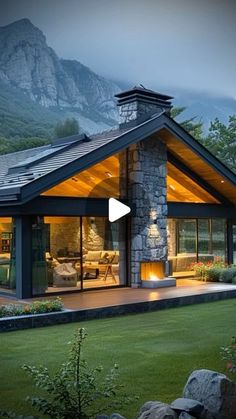 a house that is in the middle of some grass with mountains in the back ground