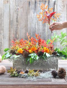 someone is placing flowers in a wooden box