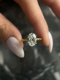 a woman's hand holding an engagement ring with a diamond on the middle finger