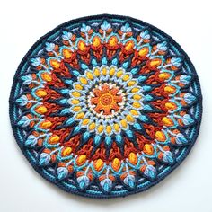 a blue and orange crochet doily on a white surface with an orange center