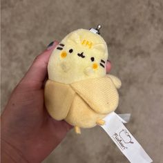 a person holding a small stuffed animal in their left hand with the tag on it