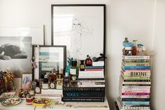 a white table topped with lots of books next to a framed photo and other items