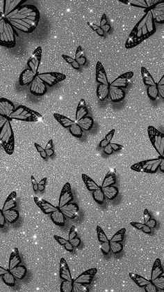 black and white butterflies flying in the air with glittery stars around them on a gray background