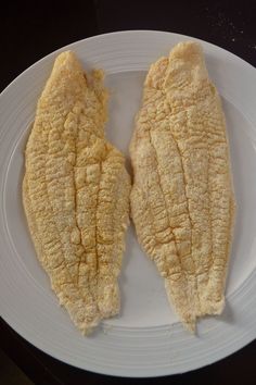 two pieces of fried fish on a white plate