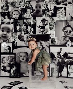 a baby standing in front of a wall with many pictures on it's sides