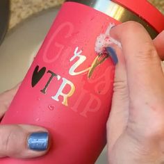 a person is holding a pink cup with writing on it and has their hand in the cup