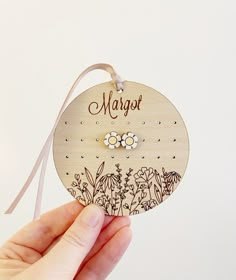 a hand holding a wooden ornament with flowers and the word marquet on it