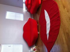 a red rug with white lips on it in the middle of a wooden floored room