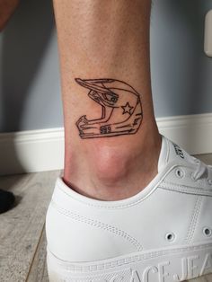 a person's foot with a helmet tattoo on the side of their leg,