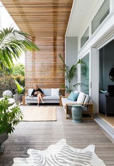 a woman sitting on top of a couch in a living room next to a plant