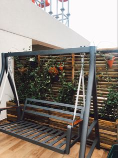 a wooden swing sitting on top of a hard wood floor next to a white building