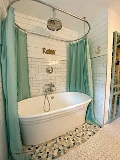 a white bath tub sitting next to a shower in a bathroom under a blue curtain