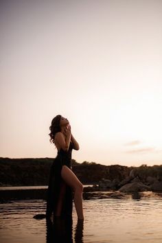 a woman standing in the water with her leg up to her face as she covers her eyes