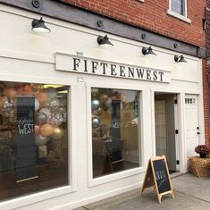 a store front with balloons in the window and a sign out front that says fifteen west