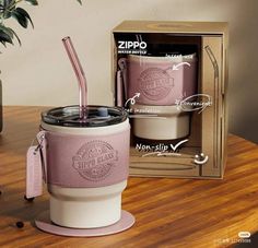 a pink cup with a straw in it sitting on top of a table next to a cardboard box