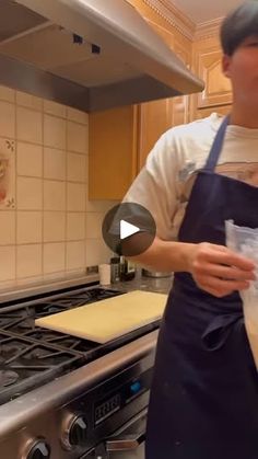 a woman in an apron is preparing food on the kitchen counter and holding a bag