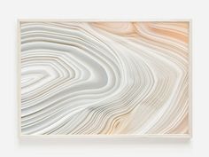 an abstract art piece with white and beige lines on it's surface, framed in a wood frame