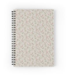 a spiral notebook with pink and green flowers on the cover, in front of a white background