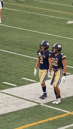 two football players are walking on the field