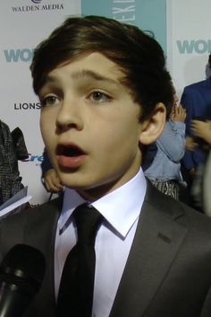 a young man in a suit and tie talking into a microphone