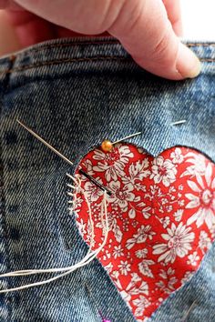 someone is stitching a heart on the back of their jean pants with pins and needles