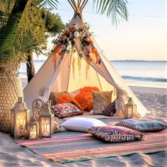 a teepee on the beach with candles and pillows