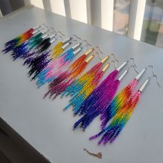 there are many different colors of beads on the table next to each other and some silver hooks