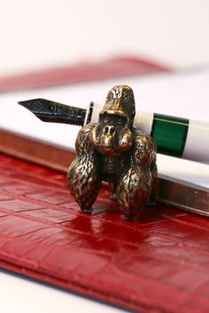 a pen sitting on top of a desk next to a teddy bear figurine