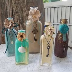 four bottles are decorated with flowers and seashells