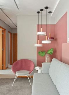 a living room with pink and white walls, two chairs and a couch in it