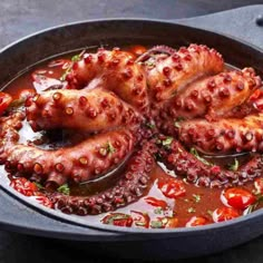 an octopus dish in a pan with tomato sauce