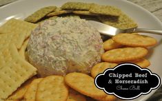 a white plate topped with crackers and a cheese ball surrounded by crackers on the side