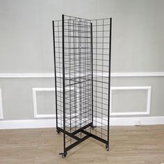 a tall black metal rack on wheels in a room with hardwood floors and white walls