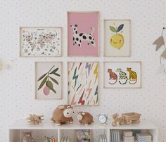 there are many pictures on the wall with animals and toys in front of them,