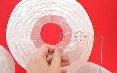 a person is holding some wire on a red background with two rolls of clear plastic