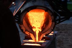 an iron melting in a large metal pot with bright orange flames coming out of it