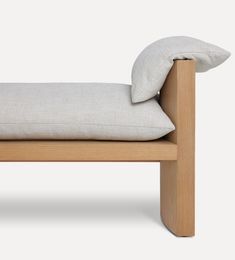 a wooden bench with two pillows on it's back and one pillow in the middle