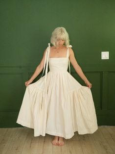 a woman in a white dress standing on the floor with her hands behind her back