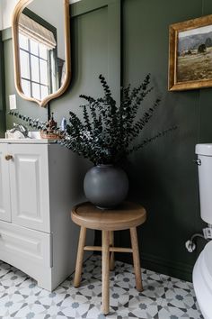 a potted plant sitting on top of a stool next to a sink in a bathroom