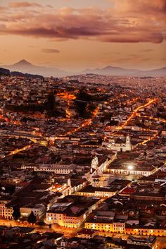 an aerial view of a city at night with the lights on and buildings lit up